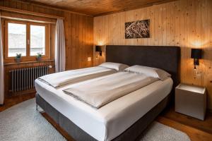 ein Schlafzimmer mit einem großen Bett an einer Holzwand in der Unterkunft Ca' del Borgo, Rooms & Suites in Poschiavo