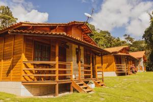 a wooden house with a porch and a grass yard at Pousada Gagno in Domingos Martins