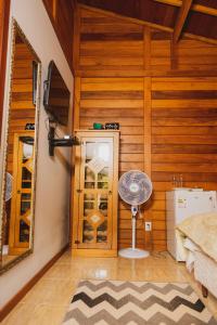 a bedroom with a wooden wall with a fan and a mirror at Pousada Gagno in Domingos Martins