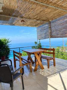 a wooden table and benches on a patio with the ocean at Erika's House in Lukovë