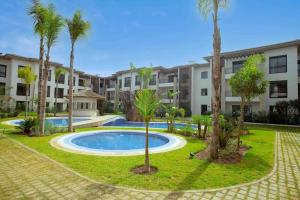 un complejo de apartamentos con piscina y palmeras en SuperHost Modern Condo 5 mins to the beach!, en Dar Bouazza