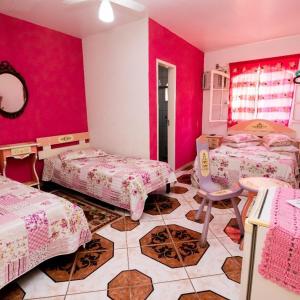 Pousada Oca Porã في كونسيرفاتوريا: غرفة بسريرين وجدار وردي