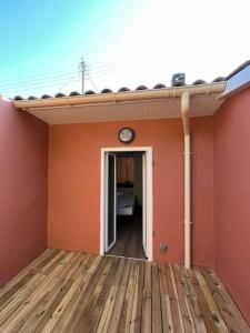 a room with an orange wall and a clock on the wall at Petite échoppe Bordeaux in Bègles