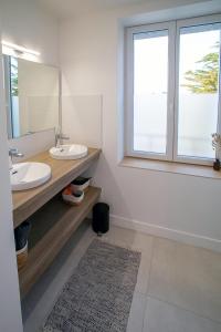 a bathroom with two sinks and a mirror and a window at Ty Meham, à 700m de la plage et Meneham, grand terrain calme in Kerlouan