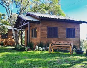 uma cabana de madeira com um banco à frente em Cabanas dos Pinheiros em São Francisco de Paula