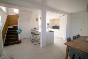 a kitchen and living room with white walls and a staircase at Ty Meham, à 700m de la plage et Meneham, grand terrain calme in Kerlouan
