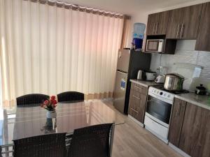 a kitchen with a table with chairs and a refrigerator at Departamento de playa con piscina en estreno in La Punta