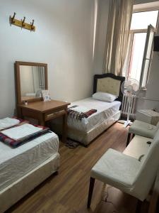 イスタンブールにあるホテル ホユックのベッド2台、テーブル、鏡が備わる客室です。