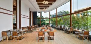 un restaurante con mesas, sillas y ventanas grandes en Kochi Marriott Hotel en Kochi