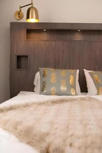 Schlafzimmer mit einem Bett mit einem Kopfteil aus Holz und Kissen in der Unterkunft Communia Hotel Residence in Stockholm