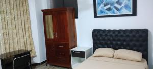 a bedroom with a bed with a black headboard and a cabinet at Makasai Tambopata 3 in Puerto Maldonado