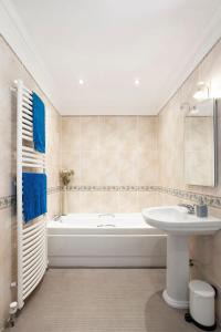 a bathroom with a white tub and a sink at Kingsley Lake View in Chew Stoke