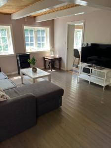 uma sala de estar com um sofá e uma televisão de ecrã plano em Koselig lite hus nær sentrum em Arendal