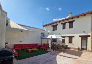 a patio with red couches and tables and an umbrella at Casa Rural Villa Cárcavas in Maello