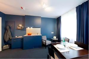 una cucina con armadi blu e tavolo e una sala da pranzo di Communia Hotel Residence a Stoccolma