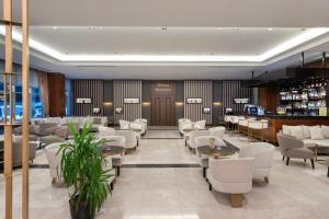 a restaurant with white chairs and tables and a bar at Miracle Istanbul Asia Airport Hotel & Spa in Istanbul