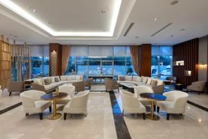 Miracle Istanbul Asia Airport Hotel & Spa في إسطنبول: غرفة انتظار مع طاولات وكراسي ونوافذ
