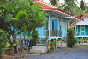 a blue house with palm trees in front of it at Patcharin Homestay in Ban Lo Pla Lai (1)