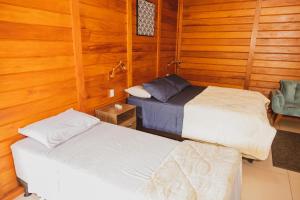Duas camas num quarto com paredes de madeira em Pousada Gagno em Domingos Martins