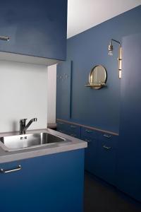 a blue kitchen with a sink and a mirror at Communia Hotel Residence in Stockholm