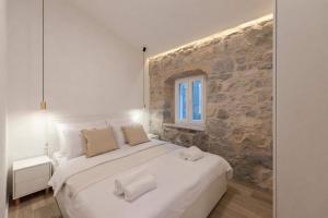 um quarto com uma grande cama branca e uma parede de pedra em Lapidea apartments em Skradin