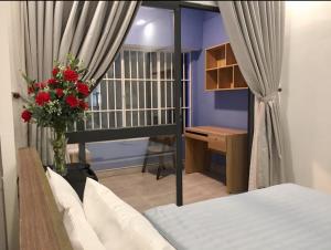 ein Schlafzimmer mit einem Bett und einem Schreibtisch mit einer Blumenvase in der Unterkunft Saigon Cozy Home " At BuiVien Walking Street " in Ho-Chi-Minh-Stadt