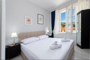una camera da letto con un grande letto bianco con asciugamani di The Bassegli - Gozze Palace a Dubrovnik