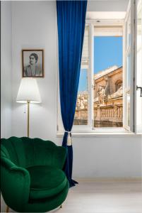 a living room with a green chair and a window at The Bassegli - Gozze Palace in Dubrovnik