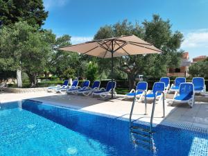 ein Pool mit Stühlen und einem Sonnenschirm neben einem Pool in der Unterkunft Mediterranean Village San Antonio in Biograd na Moru