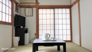uma mesa de centro com uma chaleira num quarto com janelas em friendly 民宿 em Sagamihara