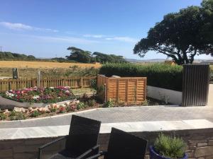 a patio with chairs and flowers in a garden at One bedroom bungalow with private garden at Parkland, near Kingsbridge in Kingsbridge