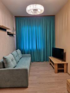 un soggiorno con divano e TV di Затишна однокімнатна квартира під Києвом a Kopylov