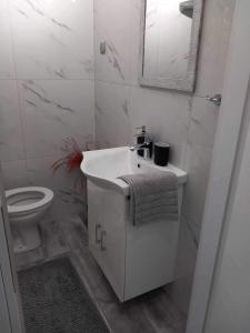 a white bathroom with a sink and a toilet at Tzanet home in Kavála