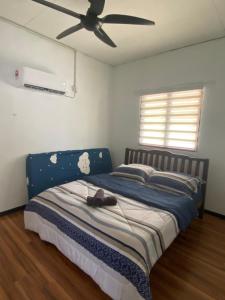 1 dormitorio con 1 cama azul y ventilador de techo en Aisyah Homestay Arau en Arau