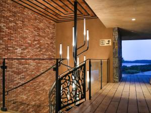 a staircase in a house with a brick wall and chandeliers at Les Regalia Hôtel & Spa in Sainte-Lucie de Porto-Vecchio