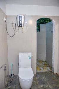 a white toilet in a bathroom with a shower at Mossy Forest Chalets in Deniyaya