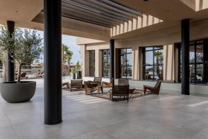 a lobby with chairs and tables and windows at Pnoe Breathing Life - Adults Only in Karteros