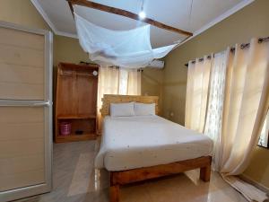 1 dormitorio con 1 cama y una ventana con cortinas en Maili 6 Private Apartments en Moshi