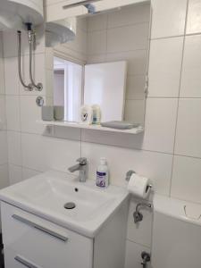 uma casa de banho branca com um lavatório e um espelho em Apartment Mejdan em Mostar