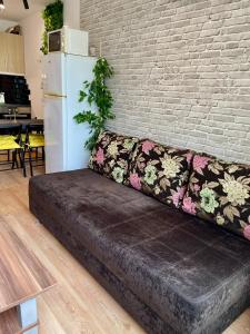 a couch against a brick wall with a white refrigerator at Budget First Sea Line Apt. FLORA in Pomorie