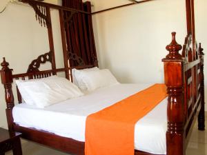 a bedroom with a large wooden bed with white sheets at Lux Suites Marrakech Apartments in Mombasa