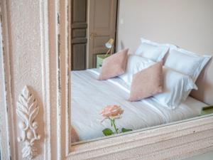 a mirror reflection of a bed with a pink rose on it at Clos des Oliviers in Mirepoix