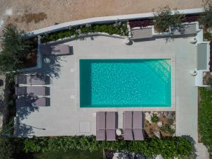 una vista sul tetto di una piscina con sedie e una piscina di VILLA CALA, Hotel Rooms&Apartments a Novalja (Novaglia)
