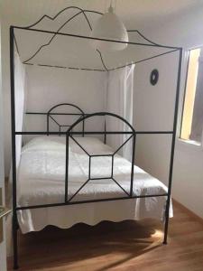 a black iron bed with white sheets and a lamp at « Chez Nath et Chris » in Saint-André-de-Cubzac