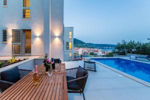 a patio with a wooden table and a swimming pool at Seaside Elegance Suites in Komiža