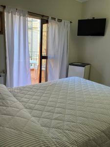 - une chambre avec un grand lit et un couvre-lit blanc dans l'établissement Hotel Catedral, à Luján