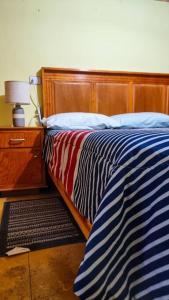 a bed with a blue and white striped blanket and a lamp at Casa en la Sierra, Mexiquillo in La Ciudad