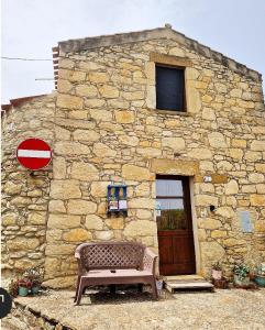 BaradiliDomus de Jara - Casa Usai的石头建筑,前面有长凳