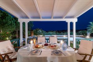 stół ze świecami i talerzami jedzenia na patio w obiekcie Villa Verdi - Your Family Oasis! w mieście Vasilikos