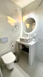 a white bathroom with a toilet and a mirror at Moustakas Beach Apartments in Adamas